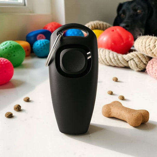 Furvana 2-in-1 black dog training whistle and clicker with a keychain, placed on a surface with dog toys.