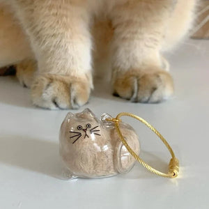 Furvana cat hair keepsake keychain featuring a clear twisted egg-shaped capsule with cat face details and gold loop