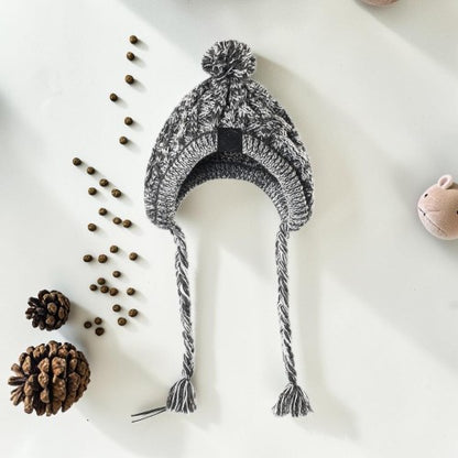 Furvana grey and white marled cable-knit dog hat with ear flaps, braided tassels, and a pom-pom on top.