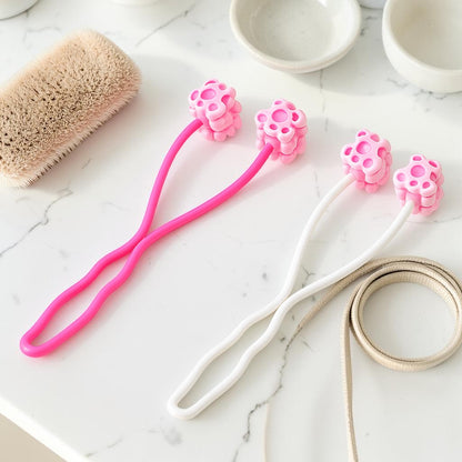 Furvana pet face roller massagers in pink and white with flower-shaped heads on a marble surface