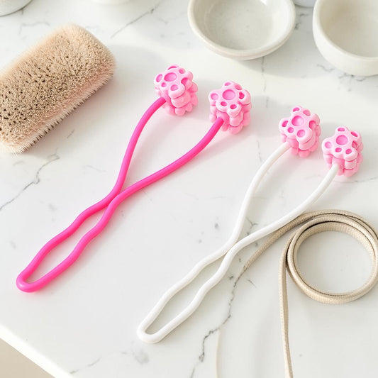 Furvana pet face roller massagers in pink and white with flower-shaped heads on a marble surface