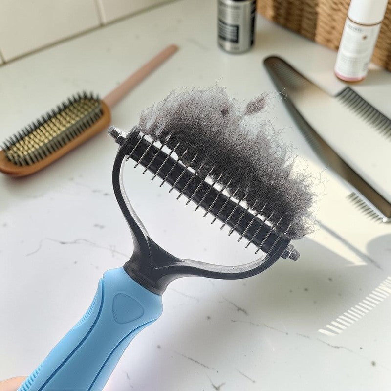 Furvana pet knot remover comb with stainless steel teeth holding a clump of removed grey dog fur on a white surface