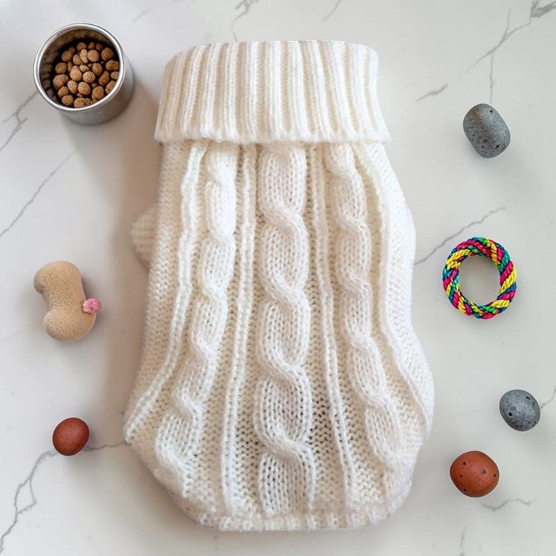 Furvana white cable knit pet sweater with a turtleneck, laid flat on a marble surface with toys and treats.