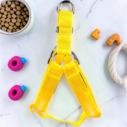 Furvana bright yellow nylon LED pet safety harness for nighttime visibility with metal D-ring on a marble surface